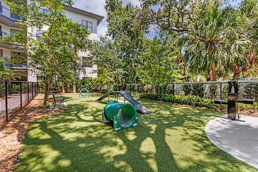 A playground with a green slide and a white building in the background.