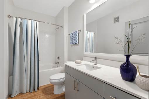 A white bathroom with a blue vase on the counter.