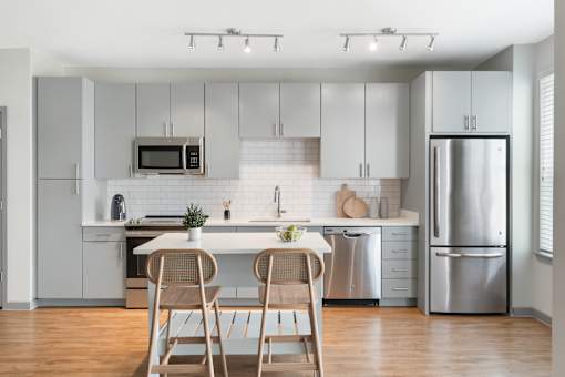 A modern kitchen with a white color scheme and stainless steel appliances.