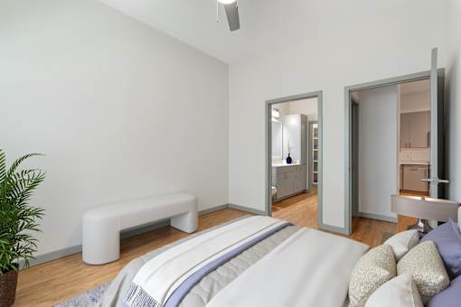 A bedroom with a bed, a bench, and a potted plant.