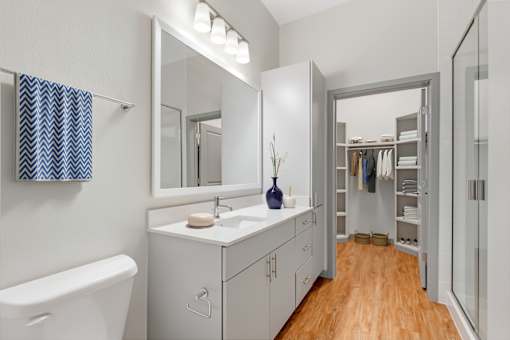 A bathroom with a white tub, sink, and wooden floor.