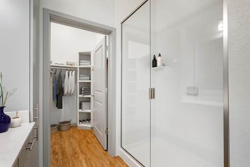 A white bathroom with a walk in shower and a white vanity.