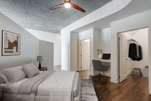 A bedroom with a large bed and a desk with a chair.