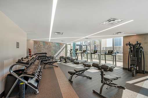 A gym with a variety of equipment including treadmills, weights, and exercise machines.