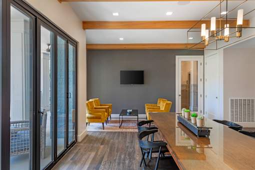 A modern living room with a long wooden table and yellow chairs.