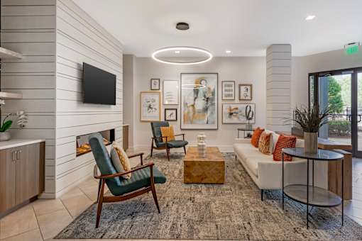 A living room with a fireplace, two chairs, a sofa, and a TV mounted on the wall.