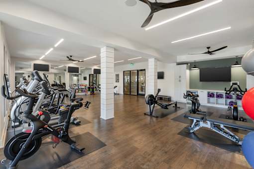 A gym with a variety of equipment including treadmills, stationary bikes, and weight machines.