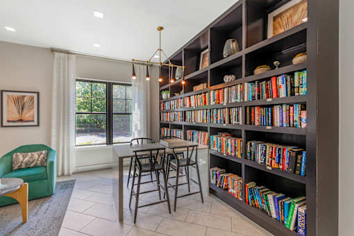 A room with a large bookshelf filled with books and a table with chairs.