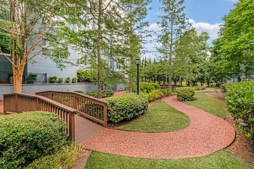 A pathway with a wooden railing on the left side and a grassy area on the right.