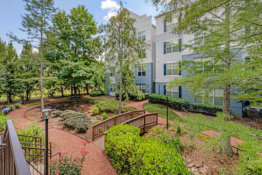 A courtyard with a brick pathway and a metal railing.