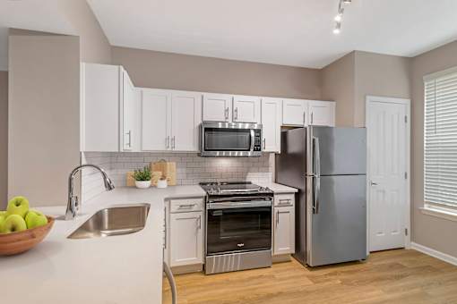 A kitchen with a stainless steel refrigerator, oven, and microwave.