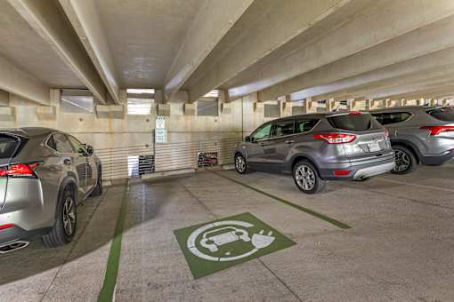 A parking garage with a green electric vehicle charging station sign.