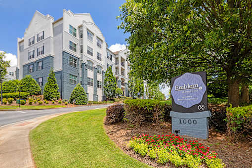 A sign for Emblem at 1000 in front of a building.