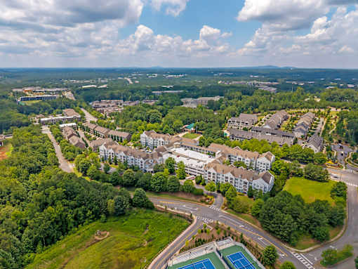 A bird's eye view of a residential area with apartment buildings, roads, and a tennis court.