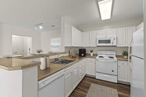 A white kitchen with a stove, microwave, and refrigerator.