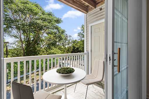 A small table with a plant on it is on a balcony.