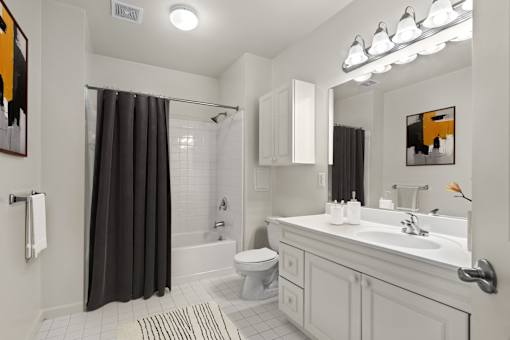 A bathroom with a white sink and a black shower curtain.