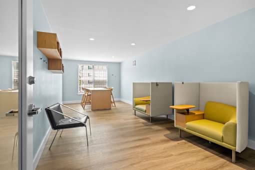 A room with a yellow couch and a black chair.