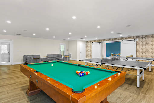 A pool table with a green cloth and a white cue ball is in the center of the room.