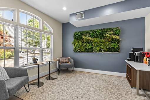 A living wall with plants in a grey room with a grey chair and a table.