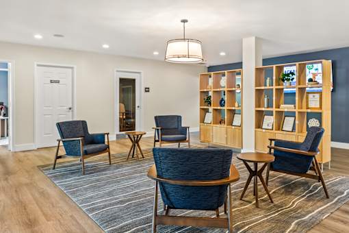 A room with blue chairs and a wooden shelf with pictures on it.