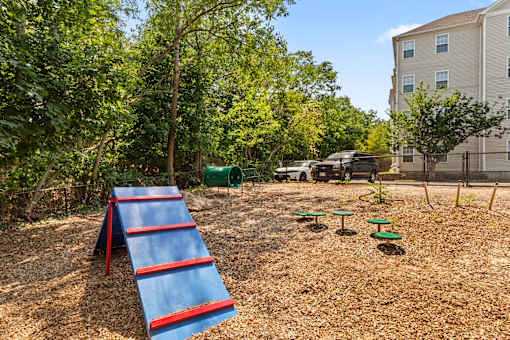 A playground with a red and blue slide in the foreground.