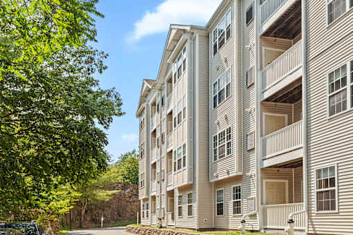 A large apartment building with balconies and a tree in front.