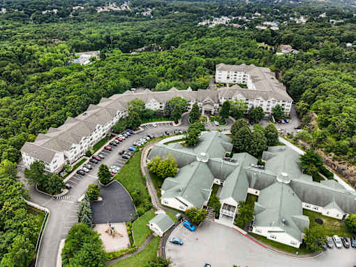A large white building surrounded by trees and a parking lot.
