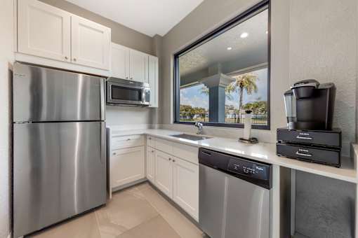 A modern kitchen with a stainless steel refrigerator, microwave, and dishwasher.