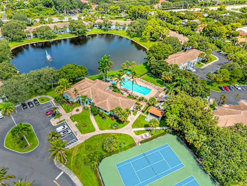 A bird's eye view of a resort with a tennis court, swimming pool, and a lake.