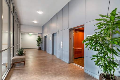 A long hallway with a bench and elevators on the right.