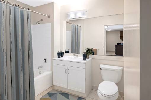 A full bathroom with large vanity mirror and white cabinetry