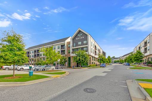 A street view of a residential area with apartment buildings and cars parked on the side of the road.
