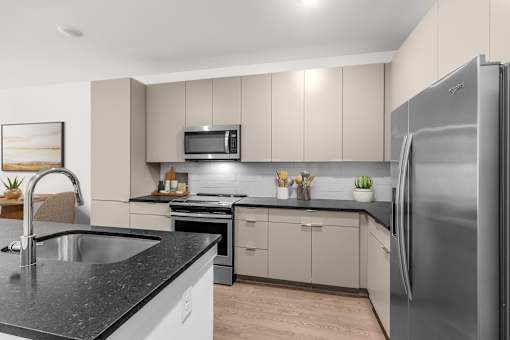 A modern kitchen with a stainless steel refrigerator, microwave, and sink.