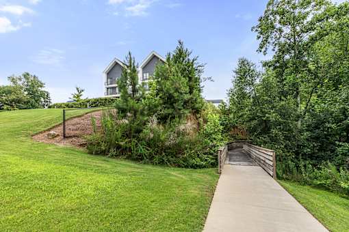 A bridge leads to a building surrounded by greenery.