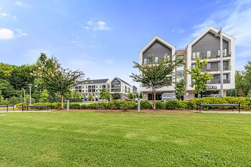 A large grassy area in front of a building with a bench.