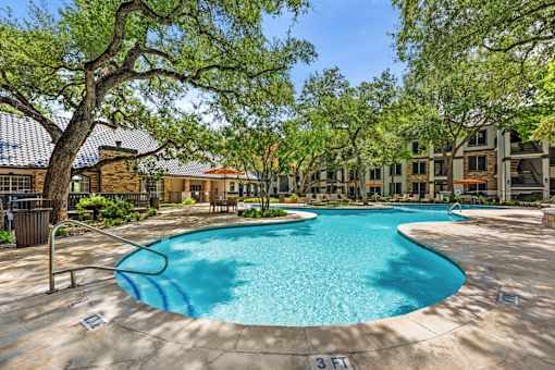A swimming pool surrounded by trees and buildings.