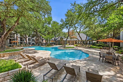 A pool surrounded by chairs and trees.