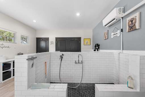 A bathroom with a white tiled shower area and a black door.