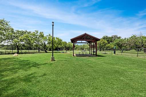 A gazebo sits in the middle of a grassy field.