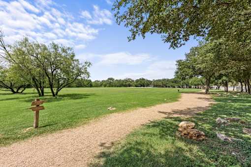 A wooden signpost stands in a grassy field with a dirt path leading off into the distance.