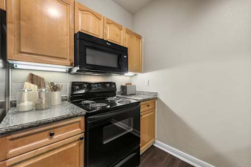 A kitchen with wooden cabinets and black appliances.