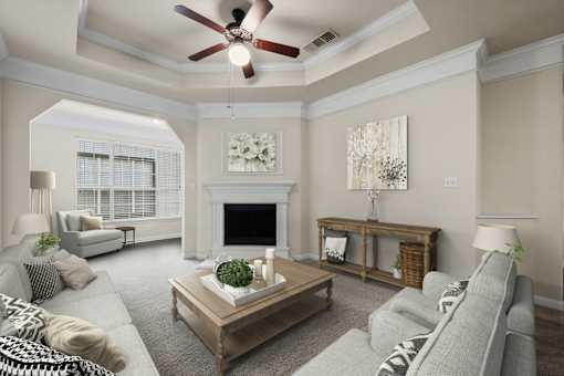 A living room with a grey couch, a coffee table, a fireplace, and a ceiling fan.