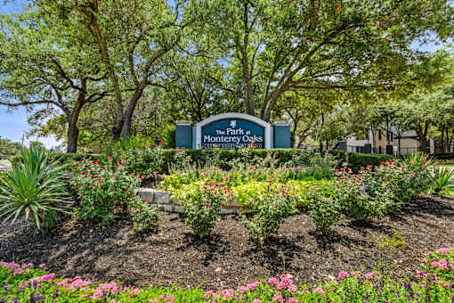 A sign for The Park at Montego Oaks is surrounded by a garden.