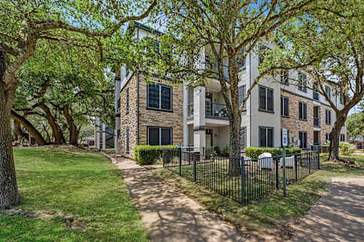 A tree-lined street with a white building on the corner.