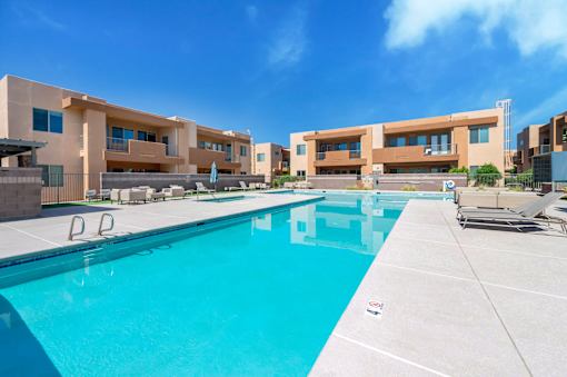A swimming pool in front of a building with a clear blue sky.