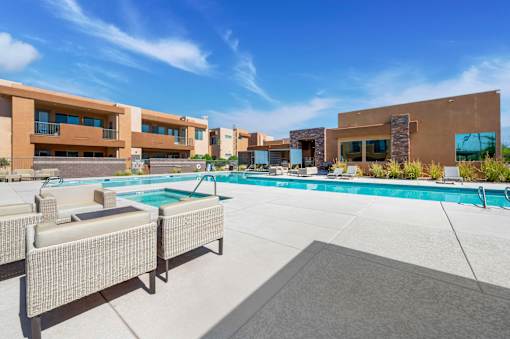 A modern outdoor pool area with lounge chairs and a building in the background.