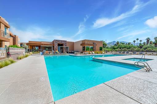 A large swimming pool with a diving board and a building in the background.