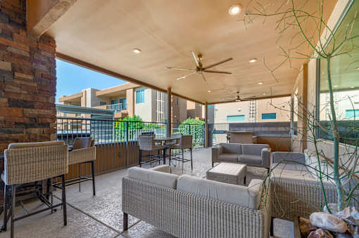 A patio with a couch, chairs, and a ceiling fan.