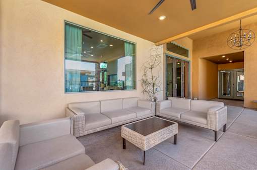A modern living room with a glass wall and a ceiling fan.